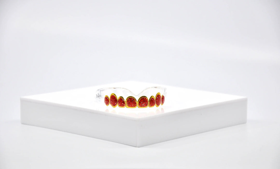 Boxing mouthguard with red and gold tooth design displayed on white platform
