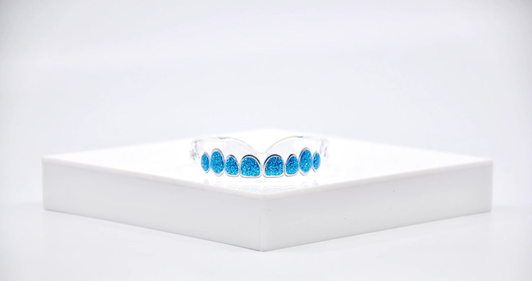 Blue glitter boxing mouthguard displayed on a white platform for protective sports gear