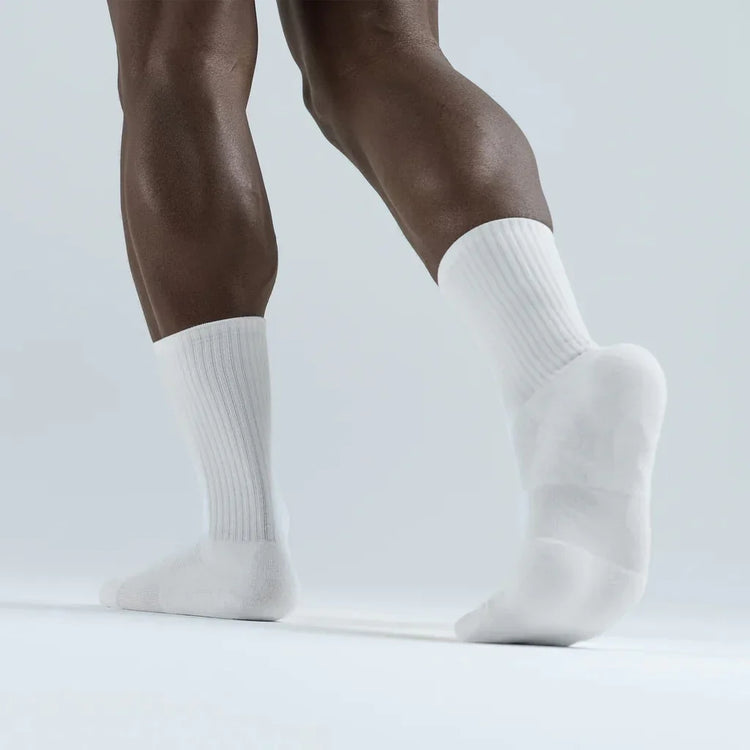 Athlete wearing white crew socks on light background, showcasing boxing training apparel.