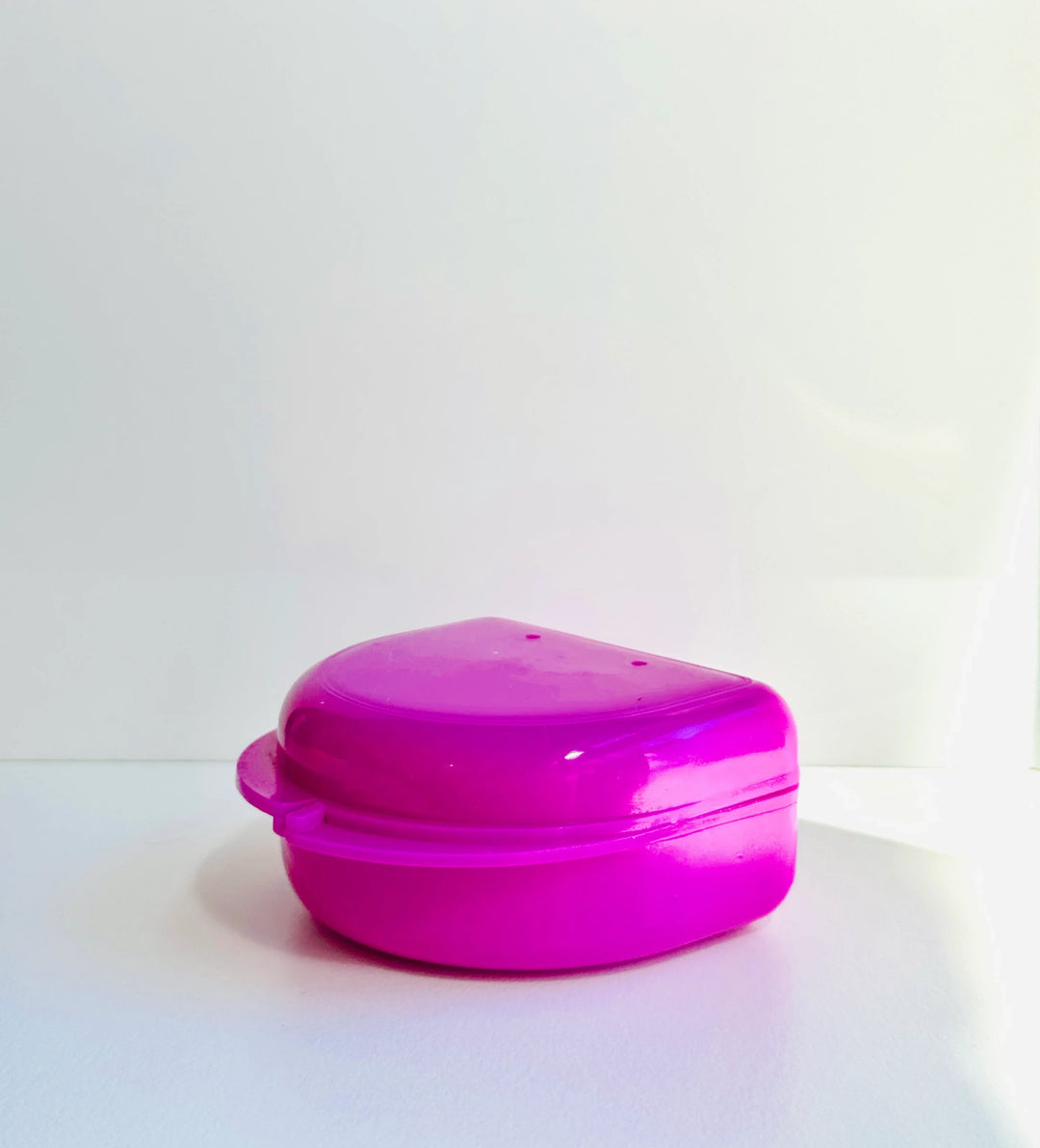 Pink plastic mouthguard case for boxing gear on a white background