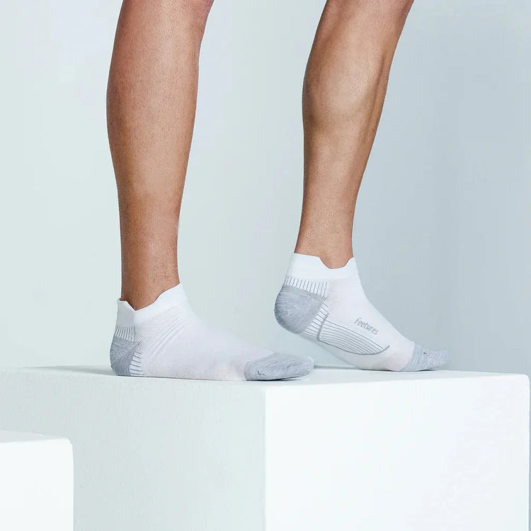 Person wearing white ankle athletic socks with gray accents on a minimalist white platform