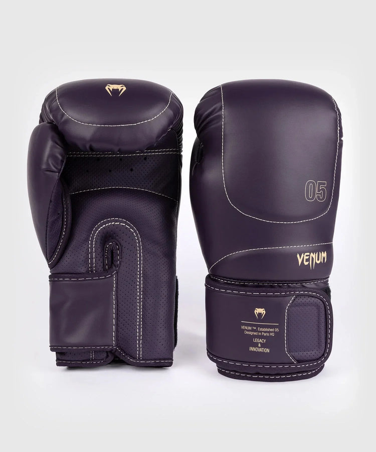 Pair of deep purple Venum boxing gloves with white stitching on a plain background